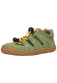 Vihreät mokkakengät, joissa on elastiset keltaiset nauhat ja mustat kiristimet, varustettuna vaaleanruskealla kumipohjalla, jossa on teksturoitu pito.