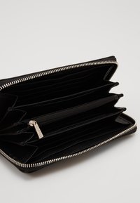 Schwarze Lederbörse mit silbernem Reißverschluss, ausgestattet mit mehreren Kartenfächern, einem zentralen Reißverschlussfach und strukturiertem Innenraum.