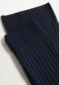 Tmavě modrá žebrovaná pletenina složená, ukazující silný elastický pas a vertikální texturované linie.