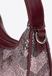 Glanzende roze pailletten tas met bordeaux leren hengsel, voorzien van een zilveren metalen ring en een textuur met geometrisch patroon.