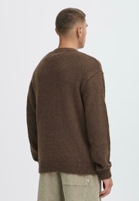 Brūns, teksturēts adījuma džemperis ar apaļu kaklaizdari un garām piedurknēm. Ribota apakšmalā un piedurkņu galos, ar brīvu piegriezumu un minimālistisku dizainu.