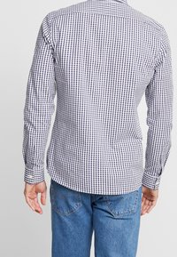 Camicia a maniche lunghe a quadri blu e bianchi con una vestibilità leggermente sagomata, polsini con bottone e orlo curvo, realizzata in un tessuto leggero.