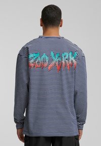 Long-sleeve striped shirt in navy and white, featuring a colorful "Zoo York" graphic on the back with a dripping paint effect.