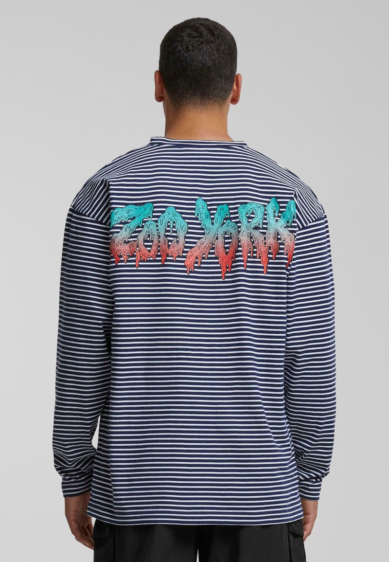 Long-sleeve striped shirt in navy and white, featuring a colorful "Zoo York" graphic on the back with a dripping paint effect.