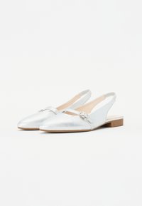 Pantofi slingback din piele argintie, cu vârf ascuțit, toc plat și un detaliu decorativ sub formă de cataramă pe curea. Textură netedă și design minimalist.
