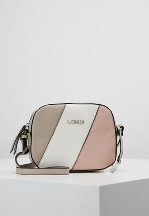Petit sac bandoulière avec des panneaux diagonaux beige, blanc et rose, logo L.CREDI, et sangle réglable sur une surface d'exposition blanche.