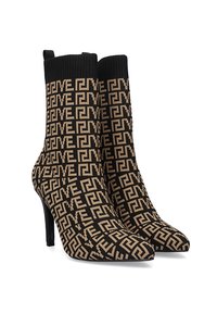 Botas de tobillo de punto en negro y marrón con un patrón geométrico, punta afilada y tacón de aguja. Parte superior acanalada para textura y ajuste.