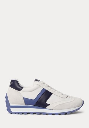 Weißer Sneaker mit blauen Wildleder- und Lederakzenten, strukturierter Sohle und Schnürsenkeln, seitlich auf einem einfarbigen Hintergrund dargestellt.