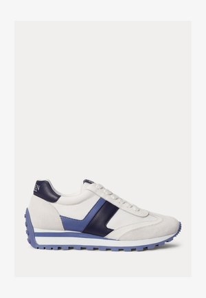 Baskets blanches avec accents en daim bleu et cuir, semelle texturée et lacets, présentées de profil sur un fond uni.