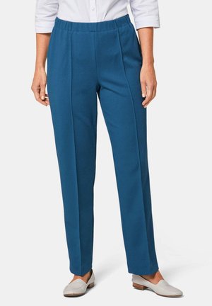 Pantalons plissés bleus en tissu texturé avec une taille élastique, associés à des chaussures à enfiler de couleur claire.