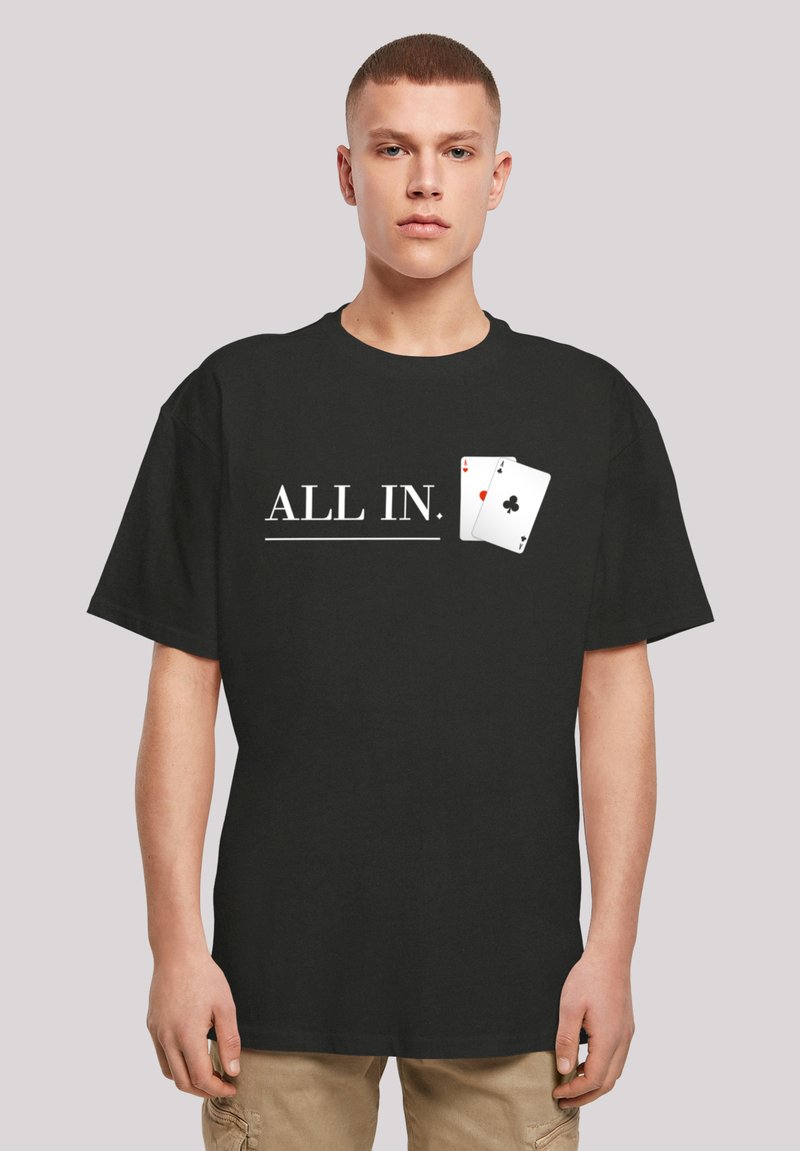 Schwarzes Baumwoll-T-Shirt mit dem Text "ALL IN." und einer Grafik von zwei Spielkarten. Kurze Ärmel, runder Ausschnitt, lockere Passform.