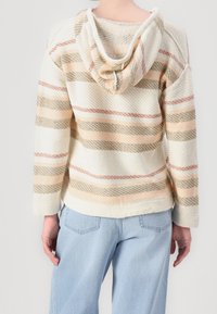 Stripet pullover hoodie i creme, med vandrette linjer i fersken og oliven. Tekstureret stof med en løs pasform og runded kant.