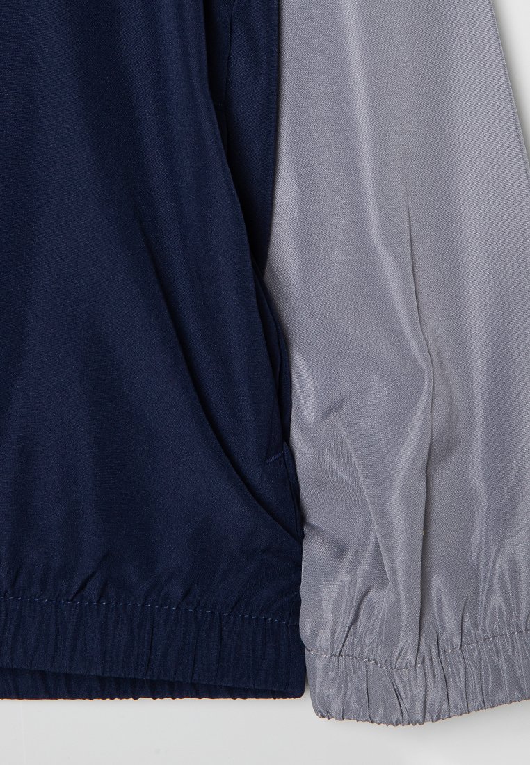 Giacca color block con corpo navy e maniche grigie. Realizzata in tessuto morbido con polsini elastici e vestibilità rilassata.