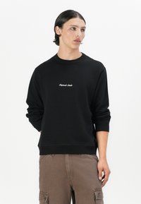 Black cotton sweatshirt with crew neck, ribbed cuffs, and hem. Features white cursive embroidered text on the chest. Casual fit.
