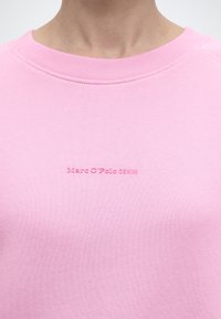 Φούτερ ανοιχτό ροζ με στρογγυλή λαιμόκοψη και μικρή κεντημένη επιγραφή "Marc O'Polo DENIM" στο κέντρο του στήθους.