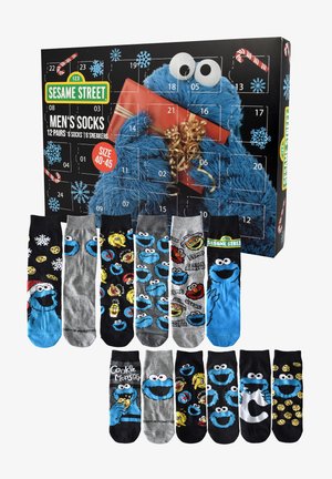 Calze da uomo a tema Sesame Street con Cookie Monster e altri personaggi, esposte con una scatola dell'aviazione di Cookie Monster.