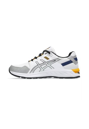 Zapatilla deportiva blanca con acentos grises, cordones negros y detalles en azul y amarillo. La suela exterior tiene textura para mejorar el agarre.