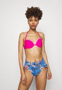 To-delt bikinitopp i fuchsia med polstring og sikksakk-kant, kombinert med høyhåpet blå bunn prydet med blomsterdesign og spenne.
