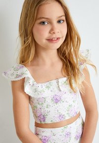 Witte bloemen crop top met lavendel- en groene accenten, voorzien van kant afgewerkte mouwen en een oogjespatroon. Gladde stofstructuur, aansluitend ontwerp.