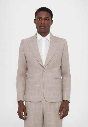 Completo grigio chiaro con un motivo a quadri rosa, caratterizzato da rever a scollatura, due tasche frontali e chiusura a due bottoni, abbinato a una camicia bianca.