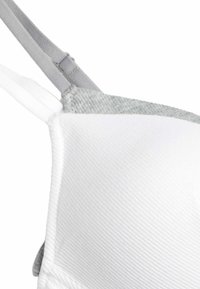 Weißer und grauer BH mit gerippter Textur, verstellbaren grauen Trägern und glattem Stoff, der eine kontrastierende Farb- und Materialkombination zeigt.