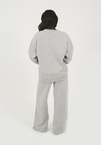 Felpa grigia e pantaloni della tuta a gamba larga realizzati in tessuto morbido, con una vestibilità rilassata, polsini a coste e scollo rotondo.