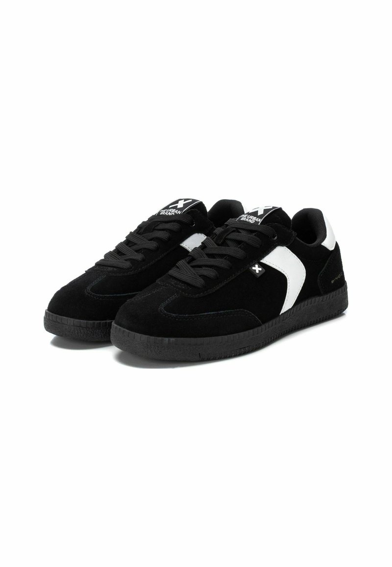 Sneaker in suede nera con accenti bianchi, con lacci neri, suola in gomma nera testurizzata e dettaglio del logo sulla linguetta.