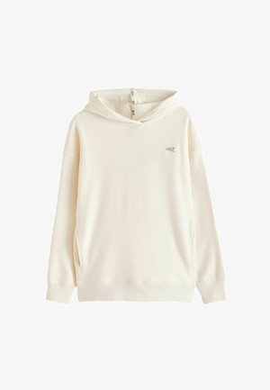 Krém színű kapucnis pulóver hosszú ujjakkal, elülső zsebekkel, és a mellkason, valamint a kapucni belső varrásán "self." hímzéssel.