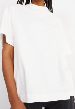 White cotton t-shirt with a relaxed fit, featuring short sleeves and a round neck. The fabric appears smooth with a subtle texture.