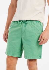 Groene katoenen shorts met een elastische tailleband en koord. Voorzien van zijzakken en een licht gestructureerde stof met gestikte zomen.
