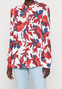 Long-sleeve blouse in lightweight fabric, featuring a white background with red and blue floral patterns, a pointed collar, and button front.