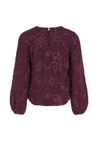 Burgunderblus med ett strukturerat blommönster i broderi, långa puffärmar och ett nyckelhål bak med knappstängning.