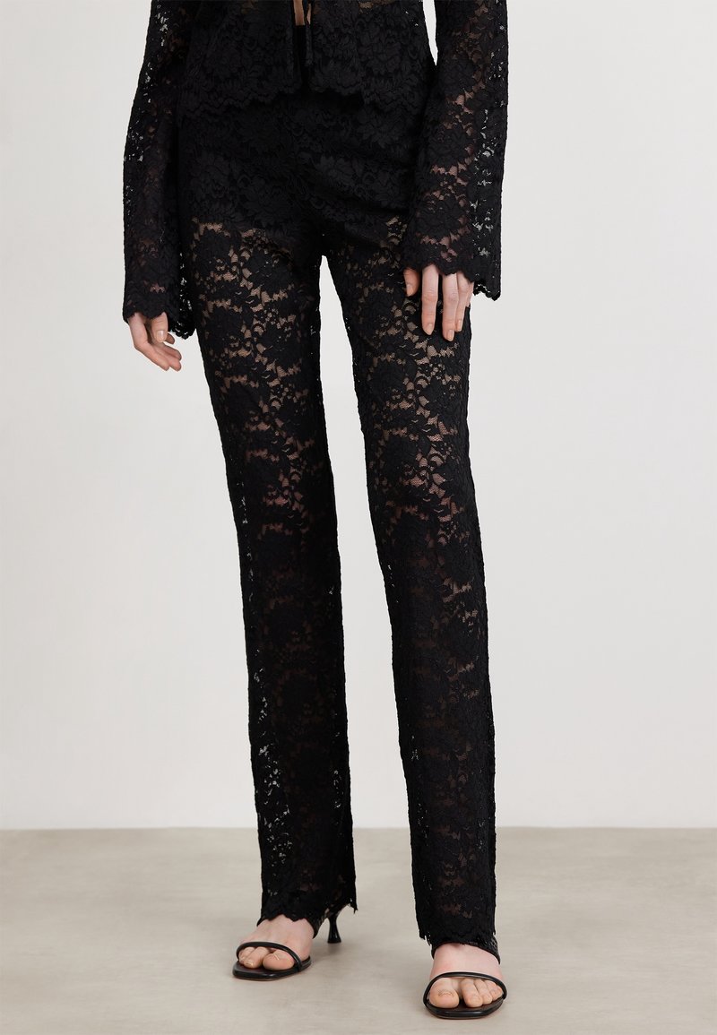 Svart spetsbyxor med intrikata blommönster, med en utsvängd bendesign och scalloped fåll. Kombination med svarta sandaler med remmar.