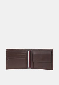 Portafoglio in pelle marrone con design a pieghe. Presenta molteplici slot per carte, una tasca con un accento a righe e un marchio impresso.