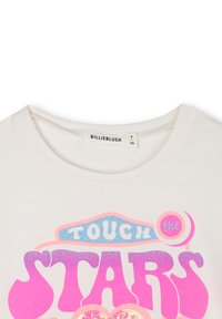 T-shirt en coton blanc avec un impressionnant texte graphique en rose et bleu "TOUCHER les ÉTOILES", avec des accents pailletés et un col rond.