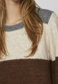 Sweter dzianinowy o kremowej bazie z brązowym dolnym fragmentem i szarymi ramionami. Okrągły dekolt i miękka faktura.