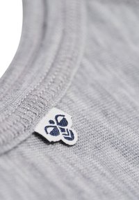 Jasnoszara bawełniana tkanina o miękkiej teksturze i żebrowanym dekolcie. Posiada małą białą metkę z granatowym logo.