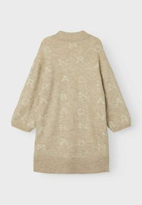 Vaahto beige neulepaita, jossa on ribbireunat ja hihansuut, ja se sisältää toistuvan kirjainkuvion vaaleammassa sävyssä. Ylisuuri, korkea kaula-aukko.