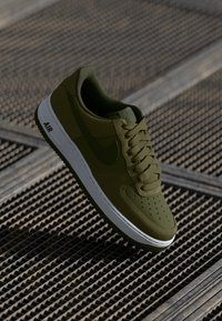 Nike Air Force 1 tenisky v olivovo zelenej farbe, s textúrovaným zvrškom, okrúhlou špičkou s perforáciami a bielou podrážkou s logom "AIR".