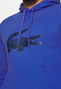 Hoodie blu in misto cotone, con un grande logo di coccodrillo nero, coulisse con punte coordinata e tasca frontale.