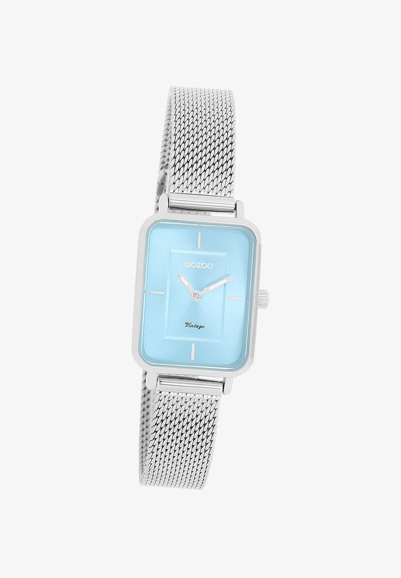Montre rectangulaire avec un cadran bleu clair et des index heures argentés. Bracelet en maille argentée, texture lisse et inscription "Vintage" sur le cadran.