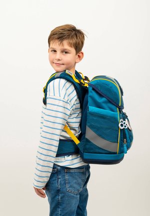 Blue backpack with yellow accents, featuring a textured design and reflective stripe. Worn on a child’s back, paired with a striped shirt.