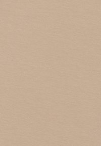 Nainen, jolla on valkoinen huivi ja beige asu, hymyilee ja pitää vaaleanruskeaa olkalaukkua neutraalia taustaa vasten.
