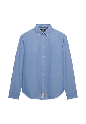 Lyseblå skjorte med lange ærmer, knapper foran, knaplukket krave og et lille hvidt mærke nederst foran.