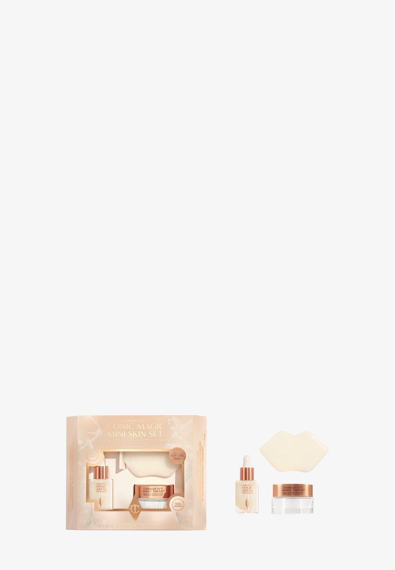 Set di cura della pelle composto da tre articoli: una bottiglia di siero in vetro, un barattolo di crema e uno strumento in silicone a forma di labbra; confezione in morbido beige con accenti dorati.