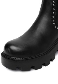 Czarna skórzana kozak z grubą, żłobioną podeszwą i srebrnymi ćwiekami wzdłuż zamka z boku.