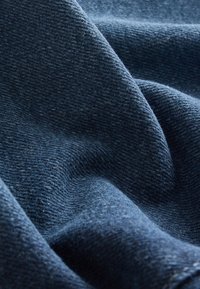 Tissu bleu foncé doux et texturé avec un motif de tissage visible et des plis doux créant de la profondeur et de l'ombre.
