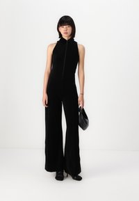 Black jumpsuit with a zip front, sleeveless design, and wide-leg trousers. Material appears soft with a smooth texture and subtle sheen.