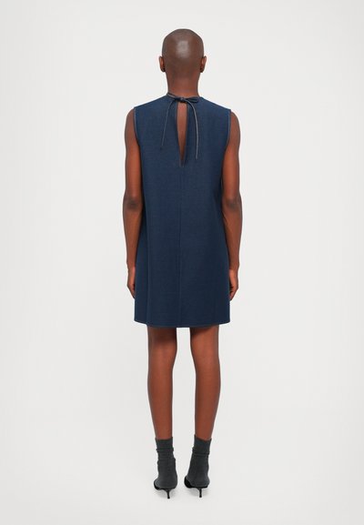 Tumši zils bezmugurkaula kleita ar apaļu izgriezumu aizmugurē, pievienota ar sasienamu mežģīni. Gluda auduma, līdz ceļiem, minimālisma dizains.