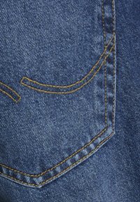 Dark blue denim fabric featuring a back pocket with yellow stitching, curved accents, and a smooth texture.